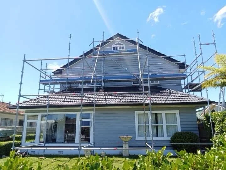 Scaffolding around a two-storey Avalon home with concrete roof tiles for exterior repairs and repainting in Lower Hutt