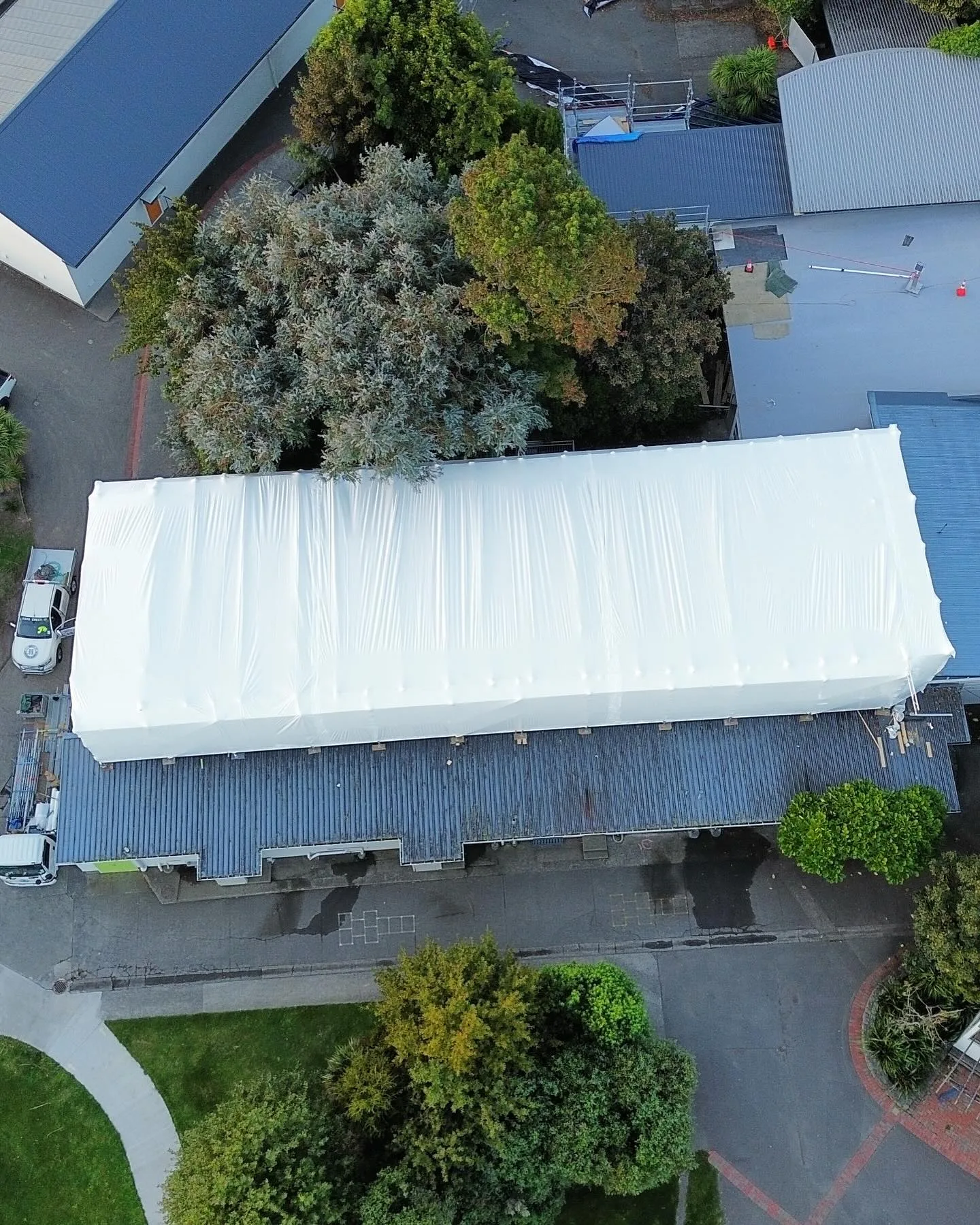 Aerial drone view of a fully completed scaffolding shrinkwrap temporary roof encapsulation over Avalon Primary School in Lower Hutt — Erect It Scaffolding Wellington
