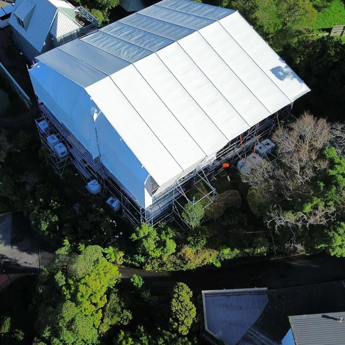 Aerial drone view of an 18m × 18m rolling roof scaffolding shrinkwrap system at 12m high on Nicholson Road, Khandallah, Wellington — Erect It Scaffolding and Altrad engineering