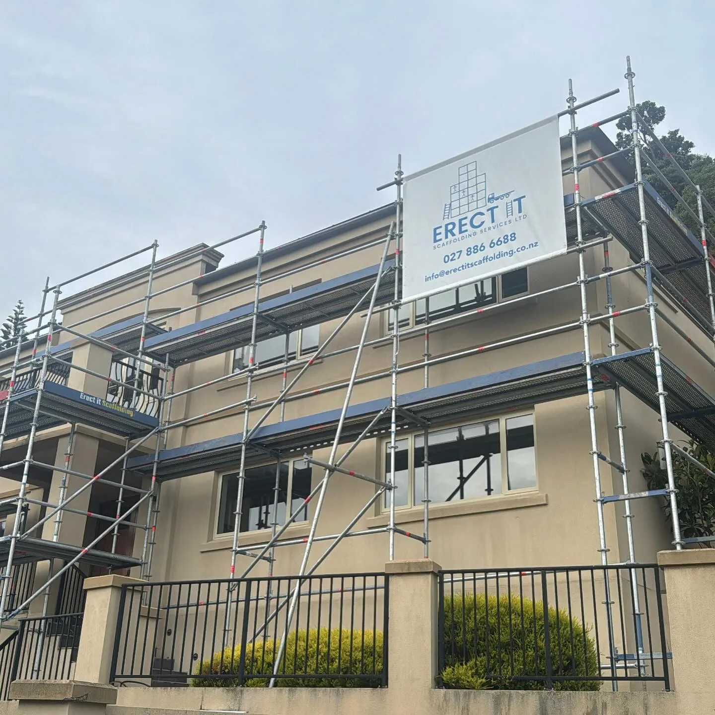 Multi-level exterior restoration scaffolding erected by Erect It Scaffolding in Strathmore Park, Wellington — full perimeter access with branded company banner visible on site