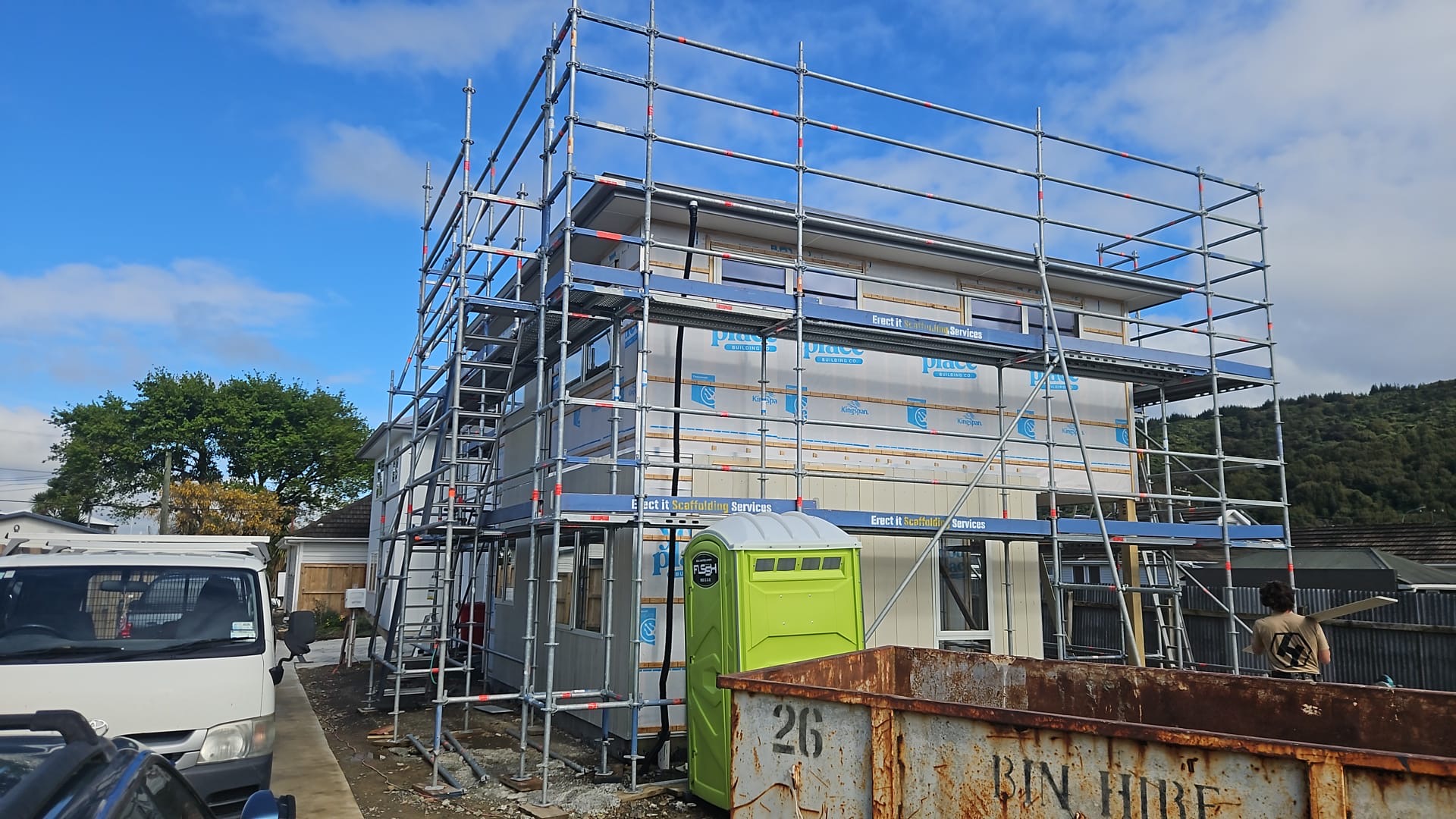Rear elevation of new residential build in Trentham, Upper Hutt at cladding stage — full perimeter Erect It Scaffolding with stair access tower, bin hire skip and Erect It truck on site