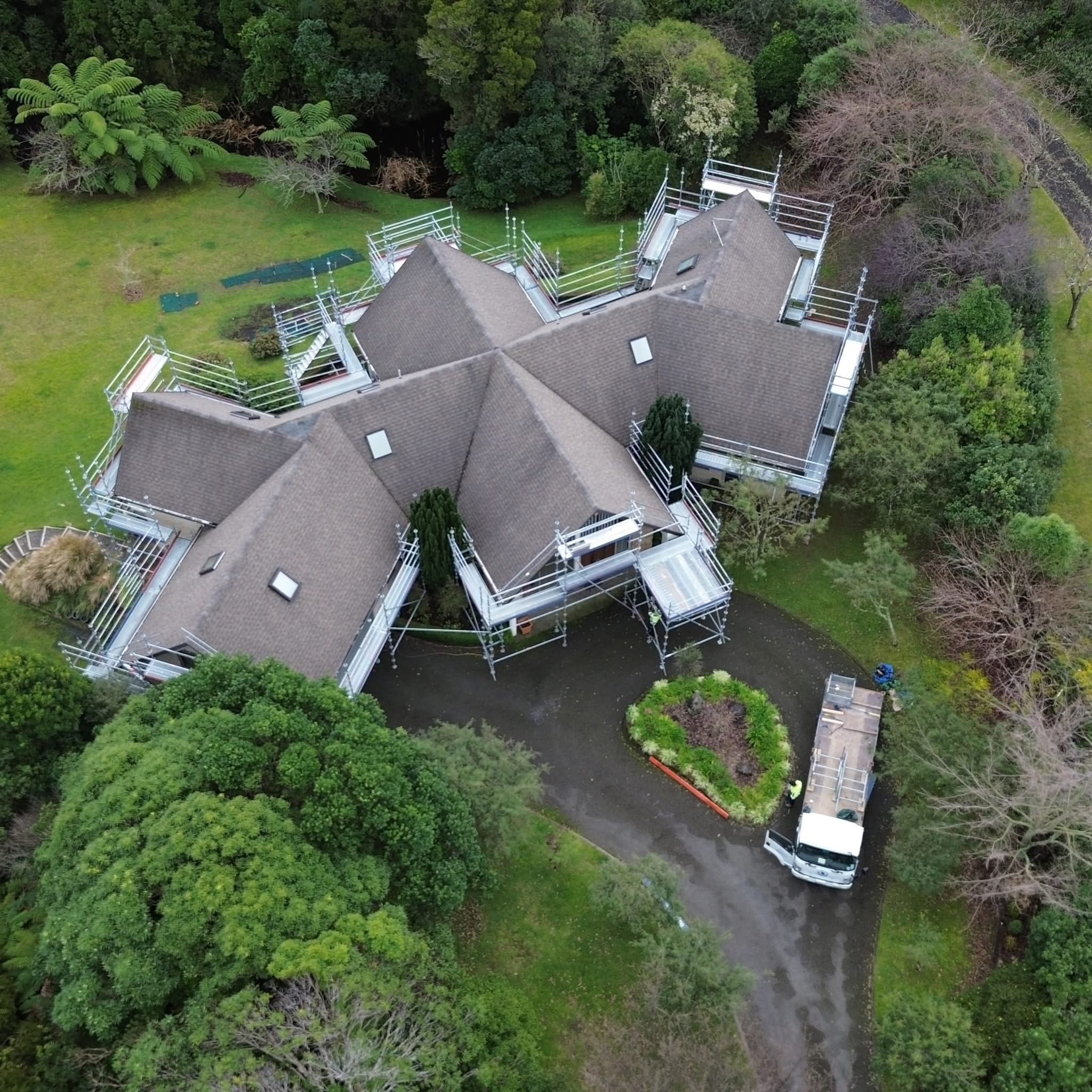 Aerial view of scaffolding and roof edge protection erected around a large Waikanae home for shingle roof repair and replacement