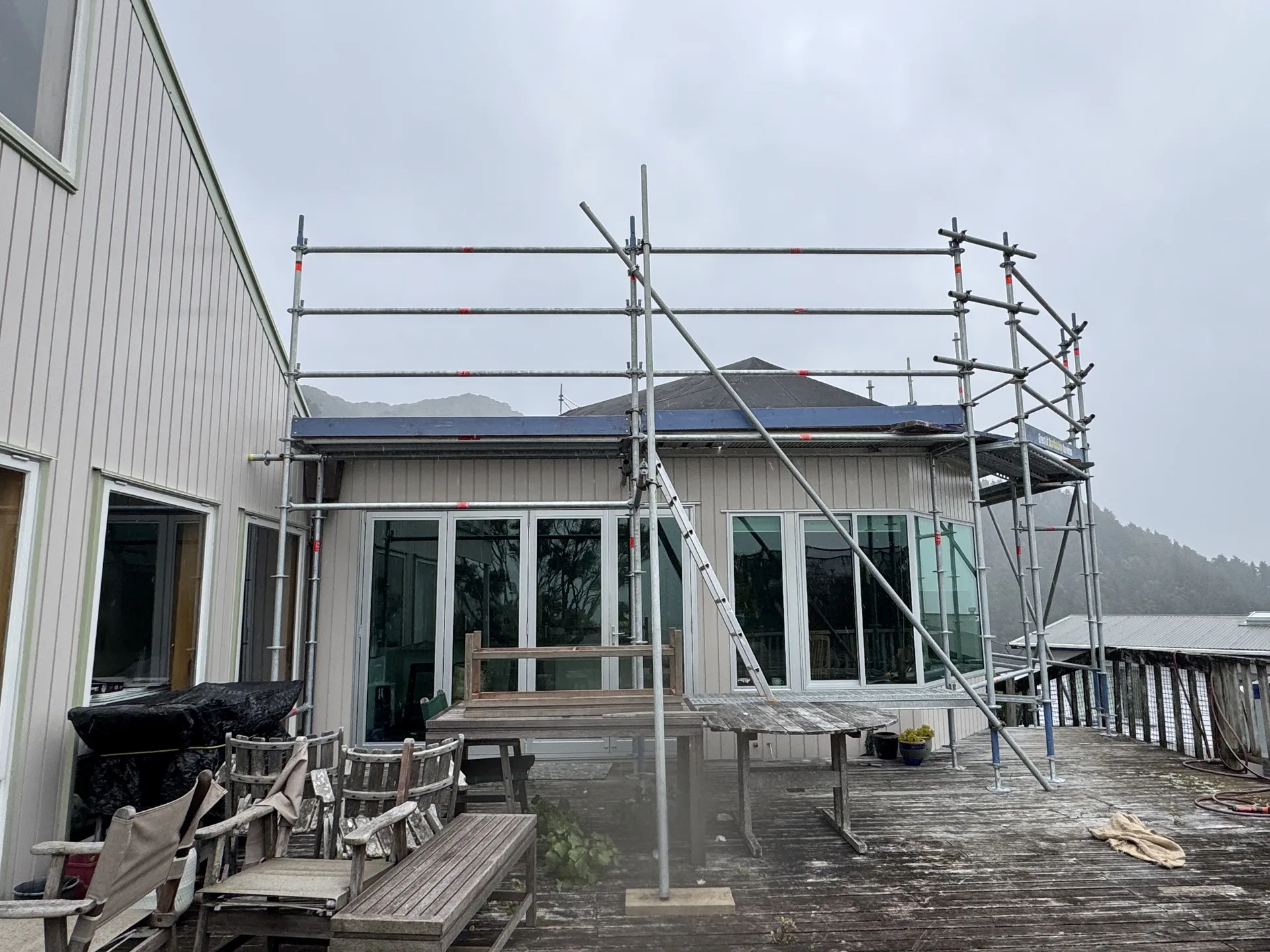 Edge protection and elevated working platform installed by Erect It Scaffolding for a membrane roof replacement on Waitohu Road, York Bay, Lower Hutt