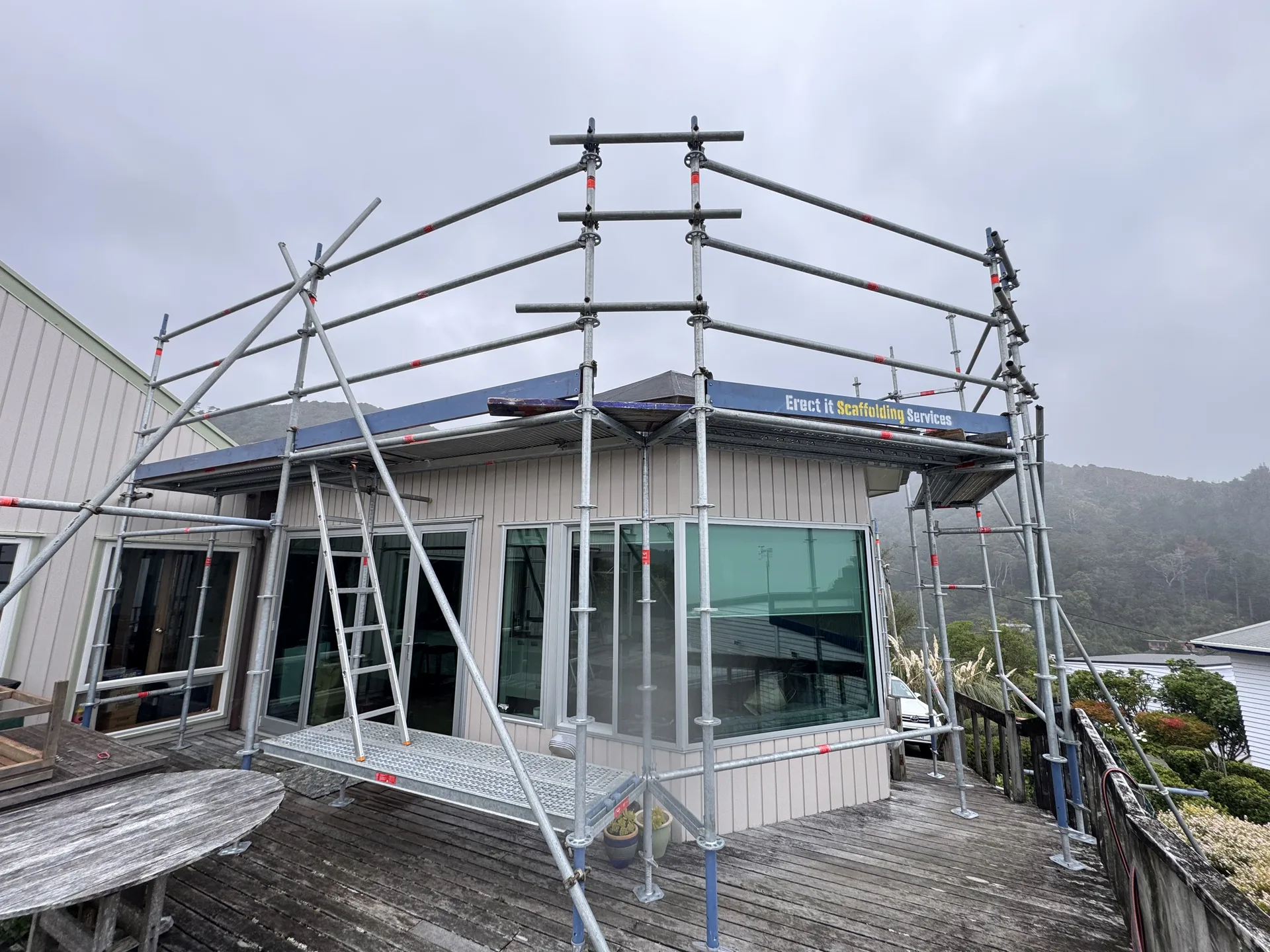 Elevated scaffolding working platforms and edge protection supporting a membrane roof replacement at Waitohu Road, York Bay, Lower Hutt