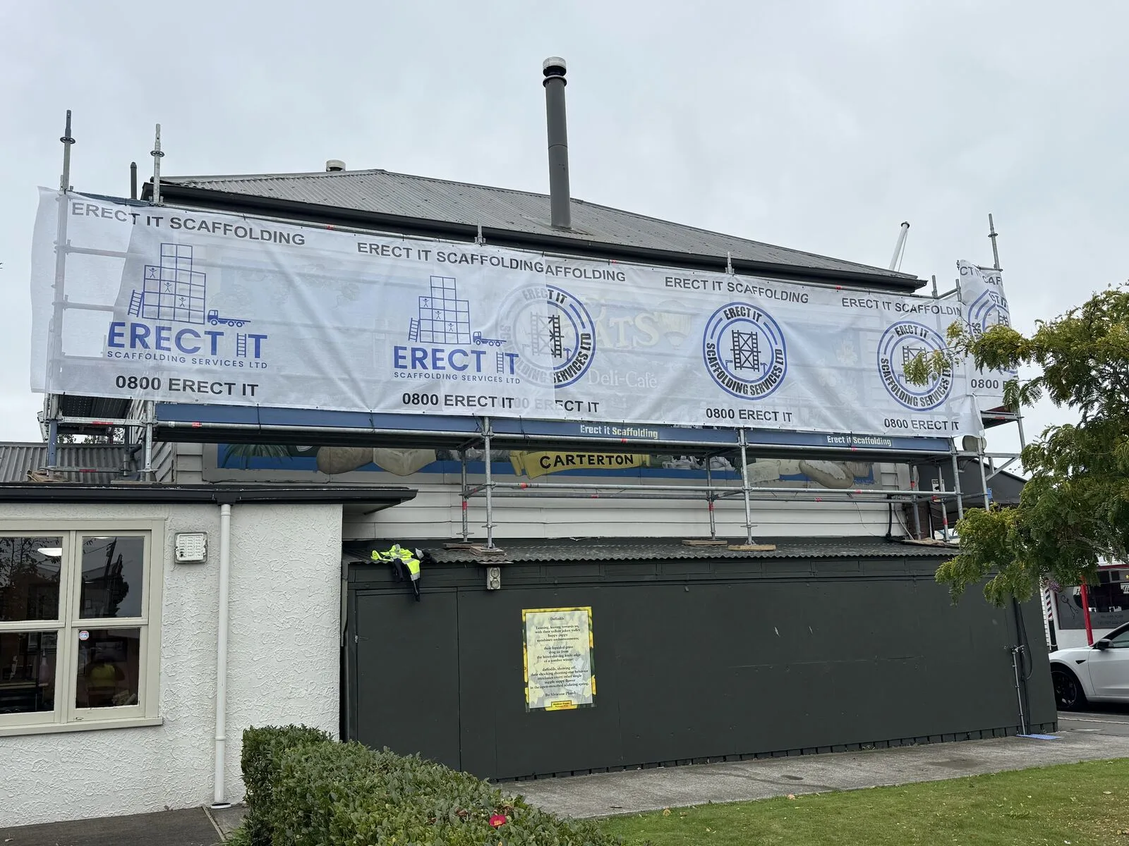 Erect It Scaffolding commercial scaffolding installation at Wild Oats Cafe, Carterton, Wairarapa — branded banners and full perimeter access for exterior works